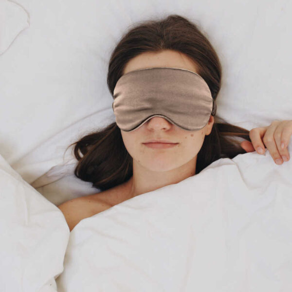 Frau mit Schlafmaske im Bett.