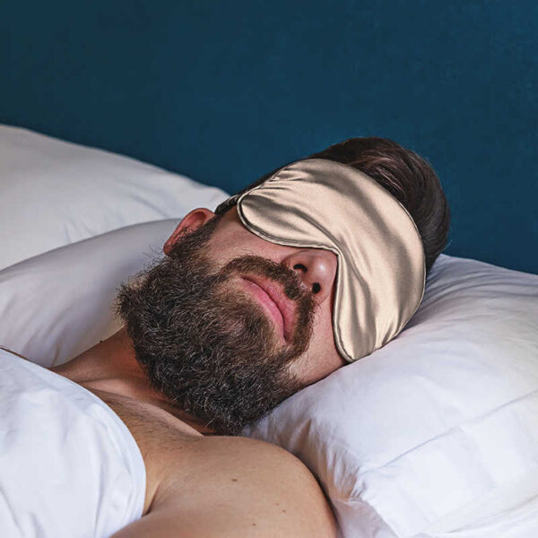 Mann mit Schlafmakse im Bett.