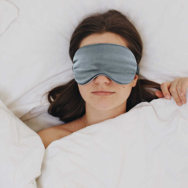 Frau mit Schlafmaske im Bett.