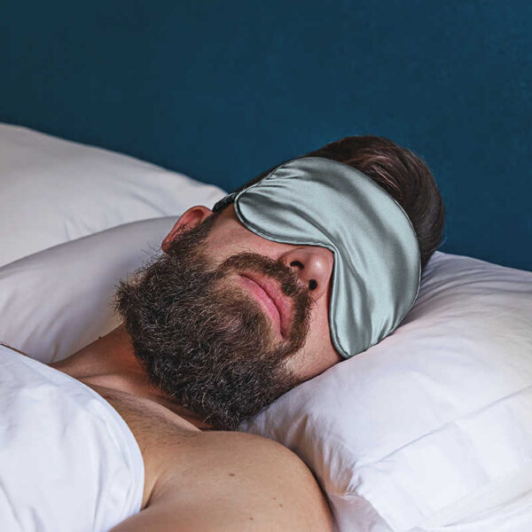 Mann mit Schlafmaske im Bett.